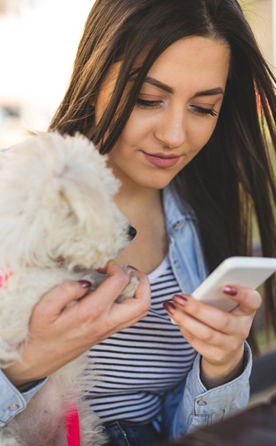 Lady with puppy using smartphone: Download our App in Waynesboro